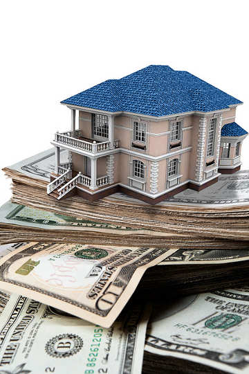 model house sits on a stack of money